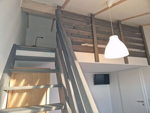 A staircase with wooden steps and metal railings, leading to a loft area with exposed beams and a hanging light fixture. - G28 Eingezäuntes Ferienhaus mit Infrarotkabine by Interhome (Burhave)