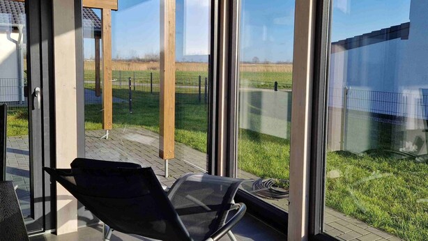 A modern outdoor seating area with a glass door leading to a grassy field. - G28 Eingezäuntes Ferienhaus mit Infrarotkabine by Interhome (Burhave)