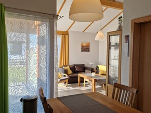 Ein modernes Wohnzimmer mit Sofa, Couchtisch und Essbereich.