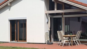 A modern house with a sloped roof, a large glass door, and a patio with outdoor furniture. - G9 eingezäuntes Haus in Randlage mit Weitblick by Interhome (Burhave)