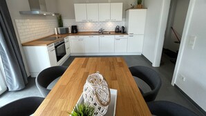 Een moderne keuken met witte kastjes, een houten aanrecht en een centraal kookeiland met stoelen.