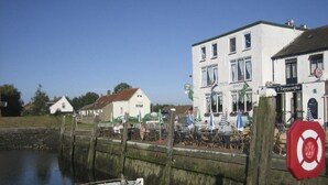 Un bâtiment situé au bord de l’eau, doté d’une terrasse et d’un quai où est amarré un bateau.
