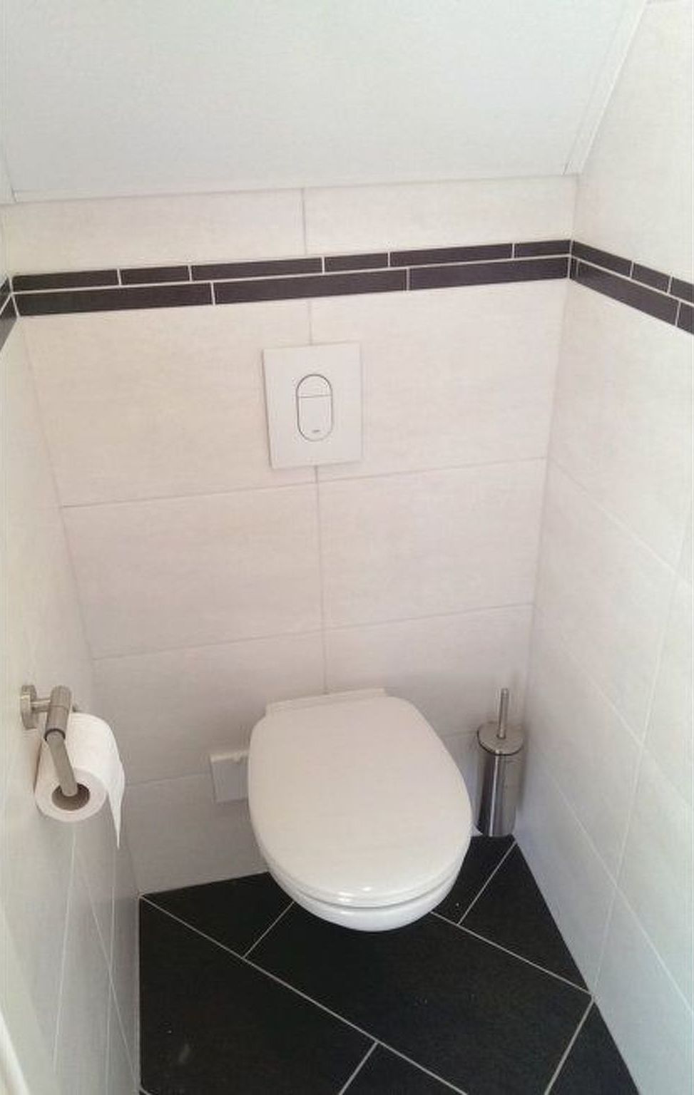 Un baño pequeño y funcional, con inodoro blanco, piso de baldosas blanco y negro, y un botón de descarga en la pared.