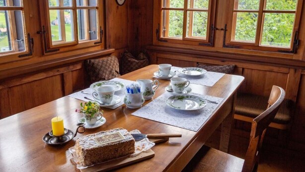 Una mesa de madera con un pastel, una tetera y velas.