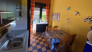 A kitchen with a sink, a microwave, and a table with a checkered tablecloth. - Vacation home L 2 by Interhome (Burhave)