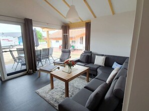 Ein modernes Wohnzimmer mit Sofa, Sesseln, einem Couchtisch und Blick ins Freie.
