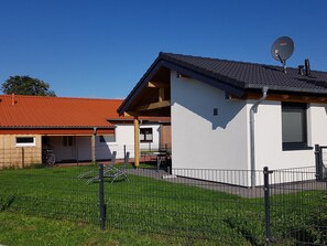 Ein Wohngebäude mit Satellitenschüssel, rotem Ziegeldach und umzäunter Garten.