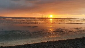 A sunset over a calm body of water with industrial structures in the background. - N4 Haus in Nordseenähe mit Terrasse und Garten by Interhome (Burhave)