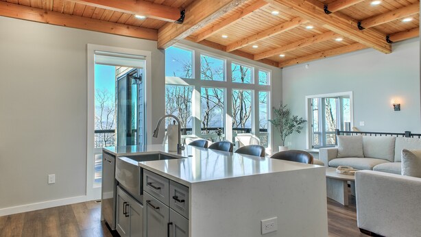 A spacious living area with a large island, a built-in kitchen, and a high ceiling with exposed beams. - Skyline Ridge | Modern New Build with Long Range Blue Ridge Mountain Views in Arden (Arden)