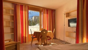 A hotel room with a bed, a desk, a chair, a table, and a TV. - Apparthotel Pöstli Nr. 106 by Interhome (Maloja)