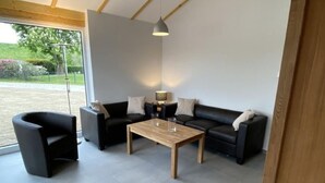 Uma sala de estar moderna com teto de madeira, um sofá, uma mesa de centro e uma grande janela com vista para o exterior.