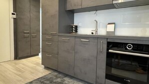 A modern kitchen with grey cabinets, a Bosch oven, and a grey rug. - Appartement mit privatem Parkplatz by Interhome (Unterterzen)