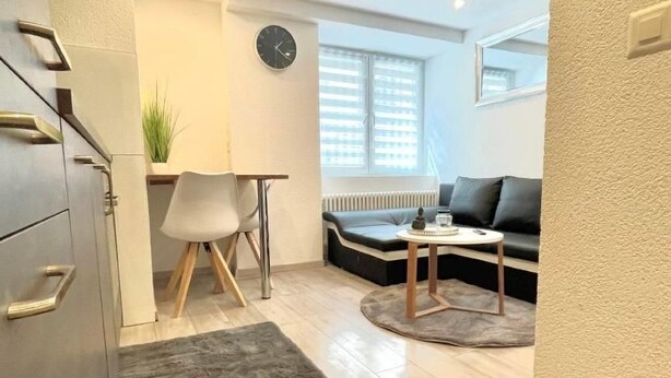 A modern living room with a sofa, a coffee table, and a dining area with a chair and table. - Appartement mit privatem Parkplatz by Interhome (Unterterzen)