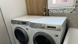 A front-loading washing machine with a digital control panel, located in a laundry room with tiled walls and a window. - mit eigener Terrasse by Interhome (Unterterzen)