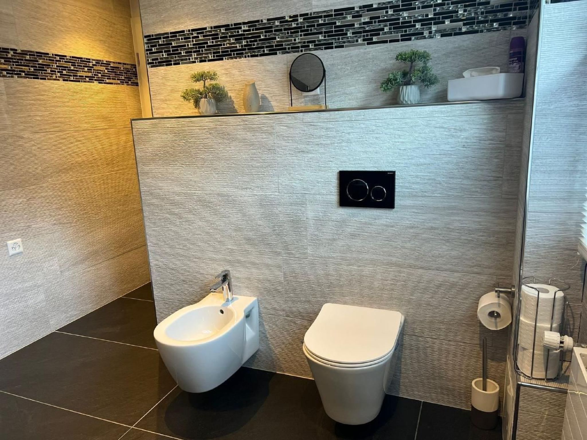 Un baño moderno con bidé, inodoro y espejo.