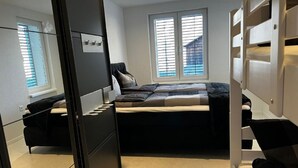 A compact bedroom with a bed, a wardrobe, and a window with blinds. - mit eigener Terrasse by Interhome (Unterterzen)