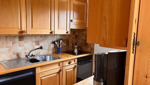 Una cocina con armarios de madera, un refrigerador de acero inoxidable, un lavavajillas y salpicadero de azulejos.