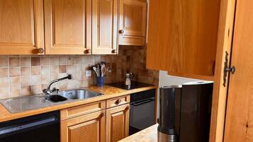 Eine Küche mit Holzschränken, einem Edelstahlkühlschrank, einer Spülmaschine und einer gefliesten Spritzschutzwand.