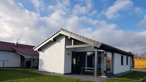 A modern single-story house with a sloped roof, large windows, and a covered patio area. - N11 Ferienhaus mit Garten in Eckwarderhörne by Interhome (Burhave)