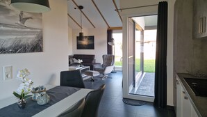 Eine moderne Küche mit integriertem Backofen, ein Essbereich mit Tisch und Stühlen sowie ein Wohnzimmer mit Sofa und Couchtisch.