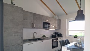 Eine moderne Küche mit grauen Schränken, einem schwarzen Spülbecken und einem Essbereich mit Tisch und Stühlen.