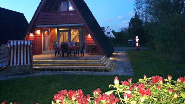 Eine Holz-Viereckhütte mit Veranda und Sitzbereich im Freien.