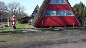 Ein rotes, dreieckiges Gebäude mit der Nummer 34, ein Leuchtturm und eine gepflasterte Fläche davor.