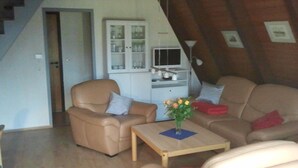Ein gemütliches Wohnzimmer mit Sofa, Sessel und einem kleinen Tisch mit einer Vase.