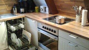 Eine Küche mit Geschirrspüler, Backofen, Herd und verschiedenen Küchengeräten.