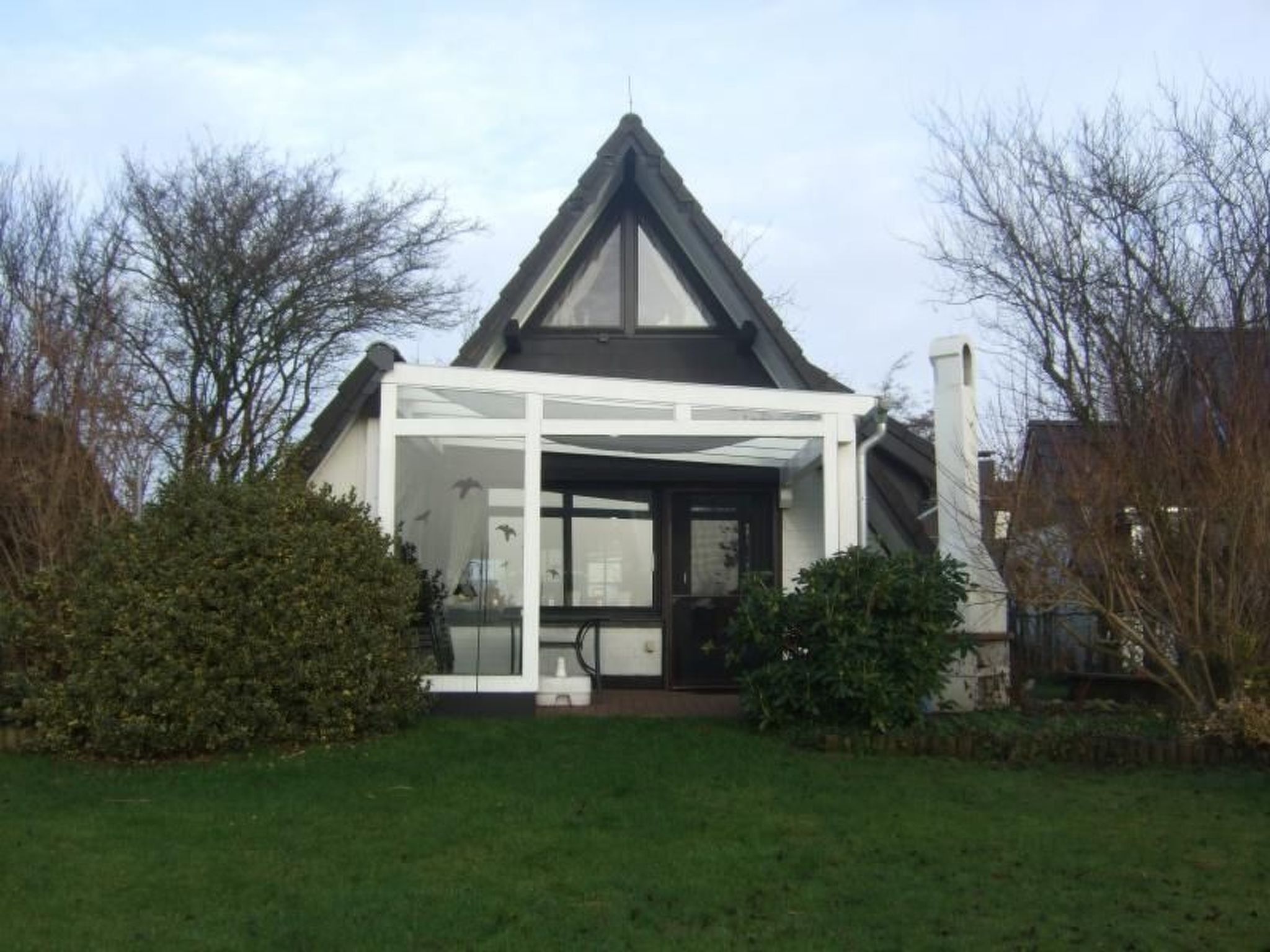 A modern house with a triangular roof, a covered porch, and a well-maintained lawn.