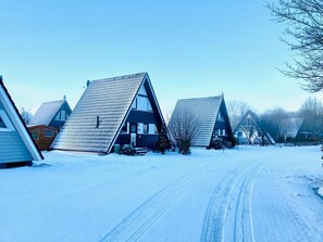 A row of snow-covered houses with steep roofs, a clear sky, and a snow-covered road. - Villa Linus by Interhome (Burhave)