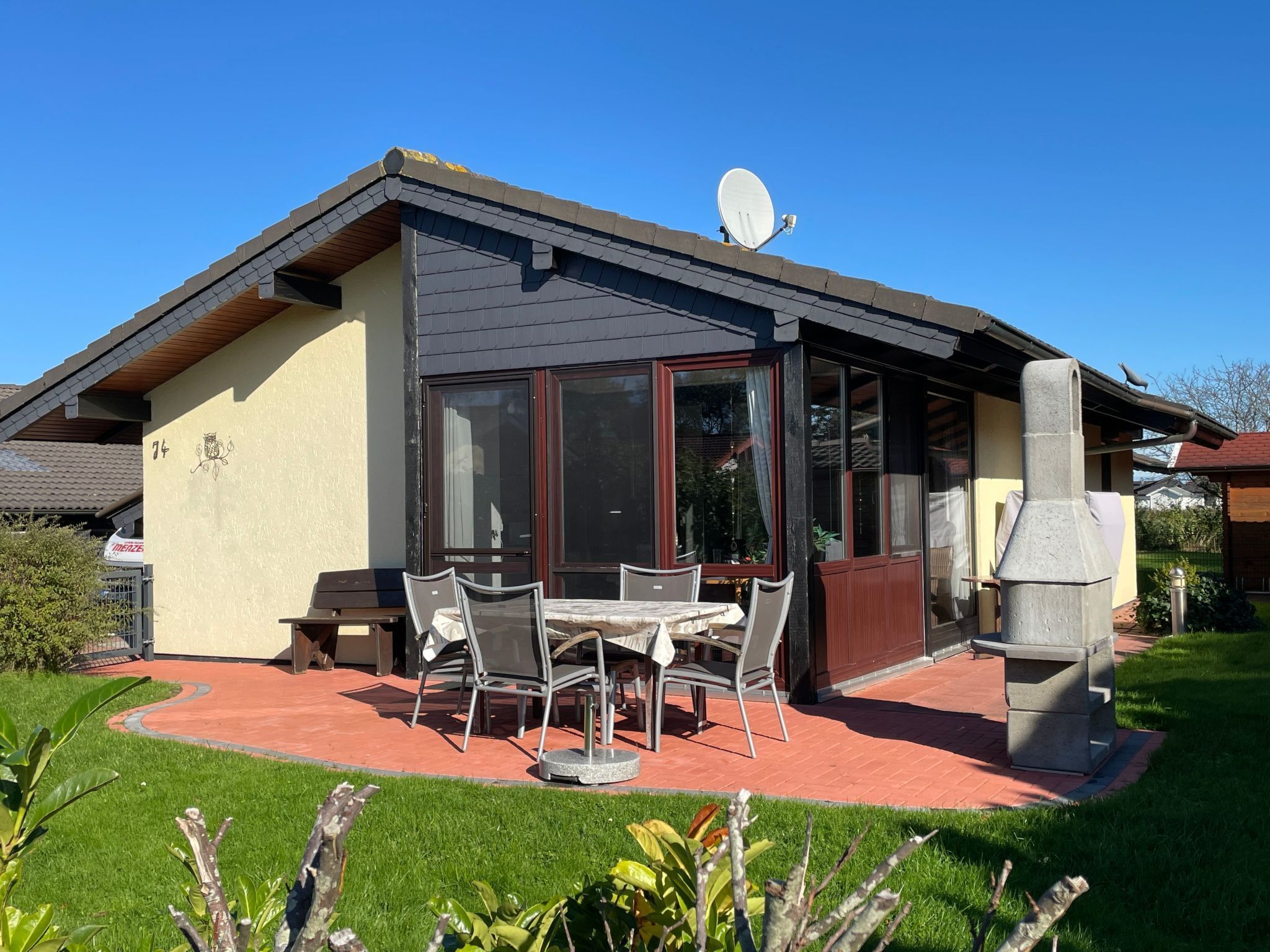 Ein Haus mit Terrasse, Grill und Satellitenschüssel.