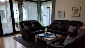 A living room with two black leather sofas, a coffee table, and a floor lamp. - K3 Ferienhaus Eul by Interhome (Burhave)