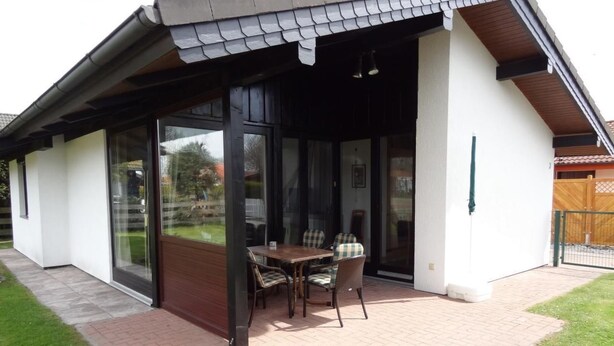 A covered patio with a table and chairs, a sliding glass door, and a brick pathway. - K3 Ferienhaus Eul by Interhome (Burhave)