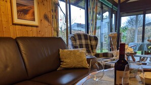 Una stanza accogliente con un divano in pelle, una poltrona a quadri e un tavolo con una bottiglia di vino e un bicchiere.