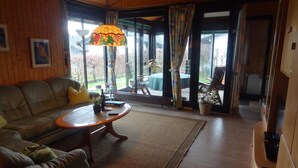 A cozy living room with a sofa, coffee table, and a large window with curtains. - Eul Ferienhaus F5 by Interhome (Burhave)