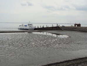 Un ferry atracado en un muelle con un pasillo de madera que lleva a un pequeño edificio.