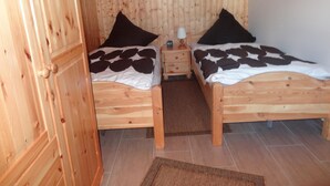 A wooden room with two beds, each with a black and white patterned bedspread, a small bedside table with a lamp, and a framed picture on the wall. - Eul Ferienhaus F5 by Interhome (Burhave)