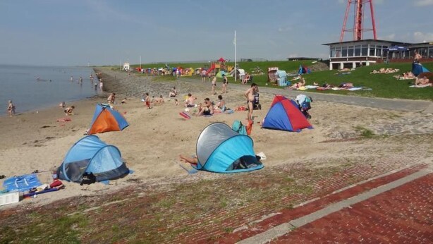 Een strand met tenten en mensen.