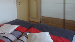 Een slaapkamer met een bed, een kledingkast en een televisie aan de muur.