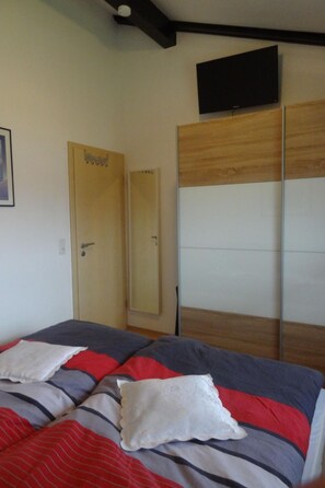 A bedroom with a bed, a wardrobe, and a television on the wall. - Hochwertiges Ferienhaus in einem Ferienpark by Interhome (Burhave)