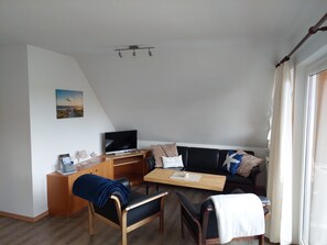 Ein modernes Wohnzimmer mit Flachbildfernseher, Holzmöbeln und einem Gemälde an der Wand.