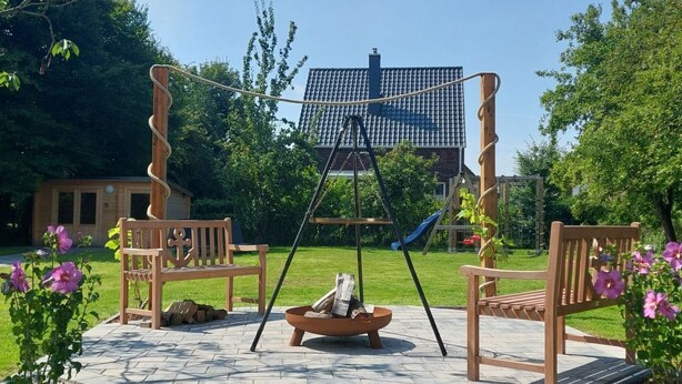 Une terrasse avec une balançoire, un foyer et un banc.