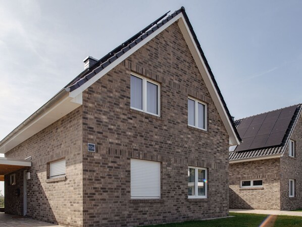 Een modern huis met twee verdiepingen, een bakstenen gevel, witte ramen en een schuin dak.