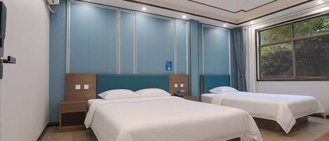 Habitación de hotel con dos camas, un ventanal amplio con vistas a zonas verdes y un diseño moderno con detalles en azul.