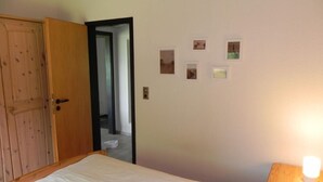 Ein Schlafzimmer mit einem Bett, einem Holzschrank, einer Tür und einer Wand mit gerahmten Bildern.