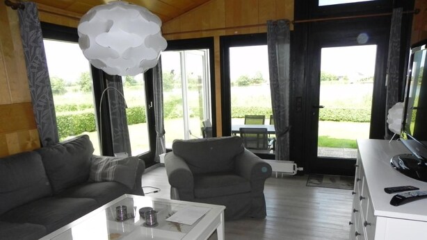 Ein modernes Wohnzimmer mit einem weißen Couchtisch, zwei grauen Sofas und einem großen Fenster mit Blick ins Freie.