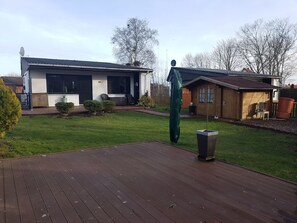 A residential property with a covered patio, a garage, and a small wooden shed. - E13 Garten/Zaun, Randlage/große Holzterrasse by Interhome (Burhave)