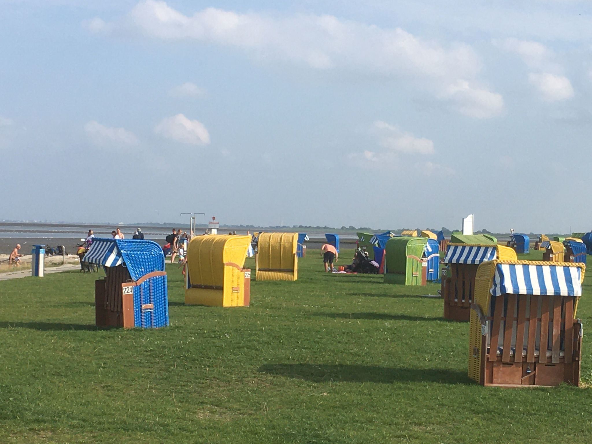 Eine Reihe von Strandhäusern mit einem Grasfeld und einem Gewässer im Hintergrund.