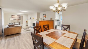 Una sala de estar moderna con una mesa de comedor de madera, sillas de madera oscura, un sofá y una lámpara de araña.